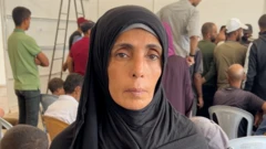 Mulher com véu preto olha para a câmera com expressão séria; atrás dela, há várias pessoas em pé e sentadas em um ambiente interno.