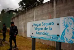 Agentes de policía hacen guardia junto a un cartel que dice "Hogar Sage Virgen de la Asunción" en la entrada del refugio infantil después de que 40 niñas murieran en un incendio el 8 de marzo, en San José Pinula, a unos 10 kilómetros al este de la ciudad de Guatemala, el 15 de marzo de 2017. (Foto: JOHAN ORDONEZ/AFP a través de Getty Images)