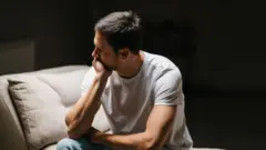 Um homem sentado em um divã perdido em seus pensamentos