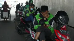 Ilustrasi mitra ojol Gojek menunggu pesanan di pinggir jalanan Jakarta, Maret 2024.