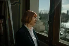 Gisèle Pelicot, de camisa branca e casaco preto, olha pela janela do Hôtel de Ville em Paris, na França