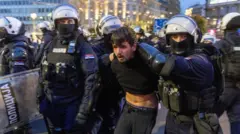 полицајци у пуној опреми држе младића 