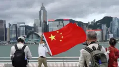 香港尖沙咀維多利亞港海旁一名男子揮舞中國國旗（中新社圖片1/7/2022）