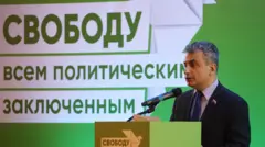Лев Шлосберг на фоне баннера с надписью «Свободу всем политическим заключенным». 