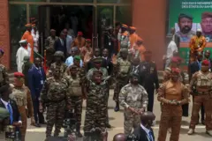 Le Général Abdourhamane Tiani du Niger lève les deux mains, à sa droite se trouvent le Colonel Assimi Goita du Mali et le Capitaine Ibrahim Traoré du Burkina Faso. Ils sont tous en tenues militaires devant des appareils photos de journalistes avec d'autres militaires derrière eux.