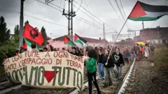 Manifestantes con banderas palestinas, una bandera con la imagen del Ché Guevara y una pancarta en italiano avanzan sobre las vías de un tren en Turín Italia.
