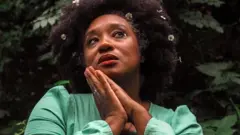 Mulher fazendo pose em jardim, com vestido verde