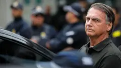 Jair Bolsonaro com olhar sério ao lado de carro