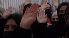 چند دختر با روسری سیاه که دست خود را بلند کردهاند.