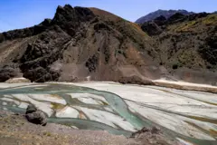 Imagem do rio Karaj na cadeia de montanhas Alborz (norte do Irã), acima da represa Amir Kabir, mostra o baixo nível da água fluindo em pequenos canais pelo seu leito, em 1° de junho de 2025. Alguns pequenos fluxos de água serpenteiam pelo leito do rio, com a areia ocupando uma área bem maior.