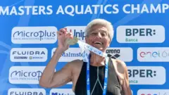 Jane Asher levanta uma medalha durante um campeonato de natação em 2022