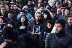 Hombres y mujeres vestidas con ropa oscura muestran su tristeza, algunas tienen en sus manos la foto del el ayatolá Alí Jamenei