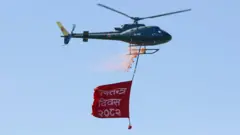 गणतन्त्र दिवस लेखिएको व्यानर बोकेको सेनाको हेलिकप्टर पुष्पवृष्टि गर्दै