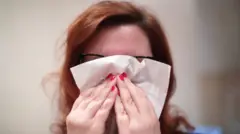 Прехлађена црвенкоса жена држи марамицу испред носа