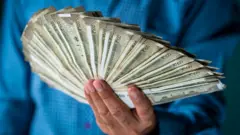 এক ব্যক্তির হাতে এক গোছা ৫০০ রুপি নোট