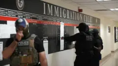 Policiais com rostos cobertos no Centro de Imigração dos EUA