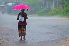 වැස්සේ කුඩයක් ඉහලාගෙන යන කාන්තාවක්