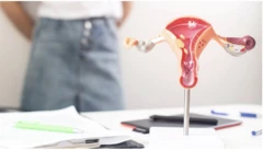 Mulher olhando para uma mesa com um modelo de anatomia pélvica feminina