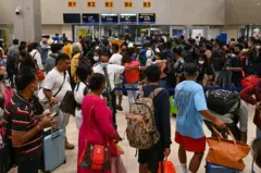 Passengers stand in queues at the Colombo International Airport in Katunayake on September 26, 2022. 