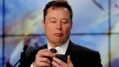 E﻿lon Musk le propriétaire de Twitter en train de manipuler un téléphone.