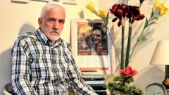 داوود سیاووش در کنار تصویری از فرزندش یما سیاووش