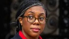 Kemi Badenoch, with her hair tied back and wearing glasses