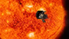 Representação artística da sonda espacial Parker Solar Probe se aproximando do sol laranja e vermelho.