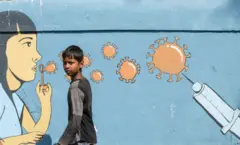 Menino passa por mural de conscientização sobre a covid