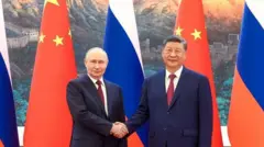 Vladimir Putin y XI Jinping se dan la mano duranre su encuentro en Pekín el 20 de mayo de 2026
