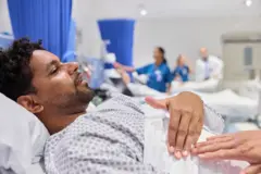  Male patient complaining about chest pain to doctor - stock photo Male patient complaining about chest pain to doctor. Man is explaining his problems while lying on gurney. He is in hospital ward.