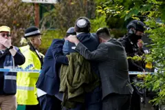 Membros da comunidade judaica confortam uns aos outros perto da Congregação Hebraica de Heaton Park em Crumsall, Manchester