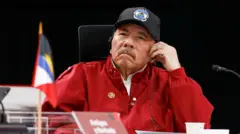Daniel Ortega ouve em fone sentado à mesa