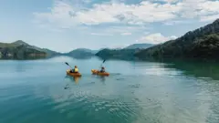 Uma dupla andando de caiaque em um lago pitoresco com montanhas ao fundo