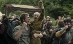 Diziden bir sahnede, ortaçağ kıyafetleri giymiş aktörler bir sahneyi canlandırıyor. Kafası kel bir çocuk, uzun boylu güçlü bir adamın kucağında, havaya zafer kutlar gibi elini kaldırmış