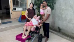 Vitor e Ianka posam para a foto com a filha Sophia, que está em uma cadeira de rodas, e Ester, que está no colo de Vitor