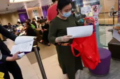 A woman leaves a bank with documents as people beat the deadline for the last day of payment for private medical insurance coverage for COVID-19 coronavirus illness and death, in Bangkok on March 19, 2020. 