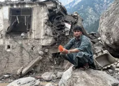 مردی افغان در کنار آوار یک خانه آسیبدیده بر اثر سیلابهای ناگهانی در شهر پارون، مرکز نورستان افغانستان، نشسته است ۲۱ جولای ۲۰۲۶