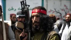 Um soldado talibã com uma longa barba e uma arma na mão