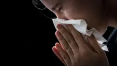 説明的な写真。女性が鼻から液体を吹きます。