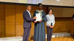 Foto of di acting acting ambassador of Nigeria to Japan, Mrs. Florence Akinyemi and Yoshikuni Watanabe, di mayor of Kisarazu, as im present di certificate from diJapanese government naming Kisarazu as di hometown of Nigerians.