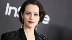 Портрет актриси на сірому фоні в чорному піджаку з блискітками та довгими сріблястими сережками