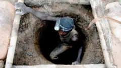 Minerador de ouro com lanterna presa à cabeça sai de uma mina subterrânea de ouro artesanal em Sadiola, no noroeste do Máli (foto de arquivo)