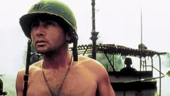 Martin Sheen representa um oficial do exército americano, com capacete, sem camisa e um barco ao fundo, em uma cena do filme 'Apocalipse Now'