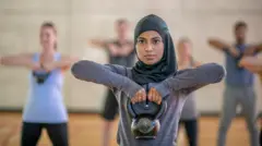 Perempuan berhijab mengangkat beban.