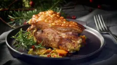 Кусок жареной свинины на блюде рядом с еловыми ветками