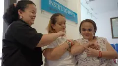 Mulheres com síndrome de Laron se abraçam em um consultório médico