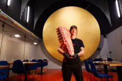 Anaí Meléndez posa em seu restaurante com uma peça de carne apoiada no ombro