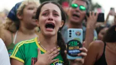 Mulher vestida com a camiseta da seleção chora enquanto segura um celular com um adesivo escrito "Sem anistia".