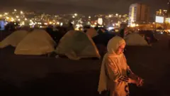 イスラエルの攻撃で孤児になった少女が、ベイルートの空き地でたきびにあたっている