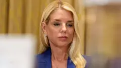 A procuradora-geral dos Estados Unidos, Pam Bondi, fotografada vestindo um terno azul e olhando para baixo durante uma audiência.